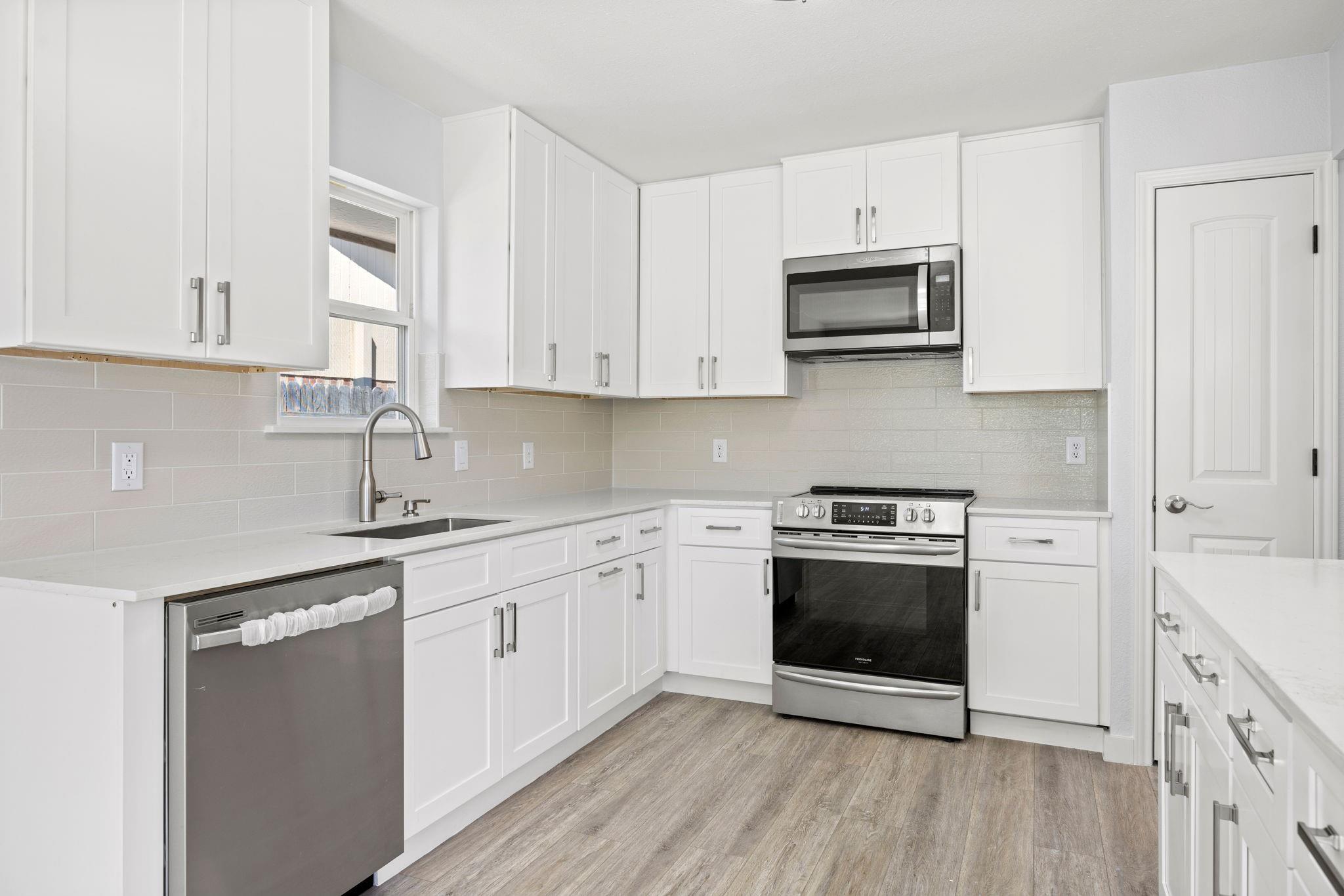 remodeled kitchen in Royse City, TX with new white granite countertops and white tile back backsplash.